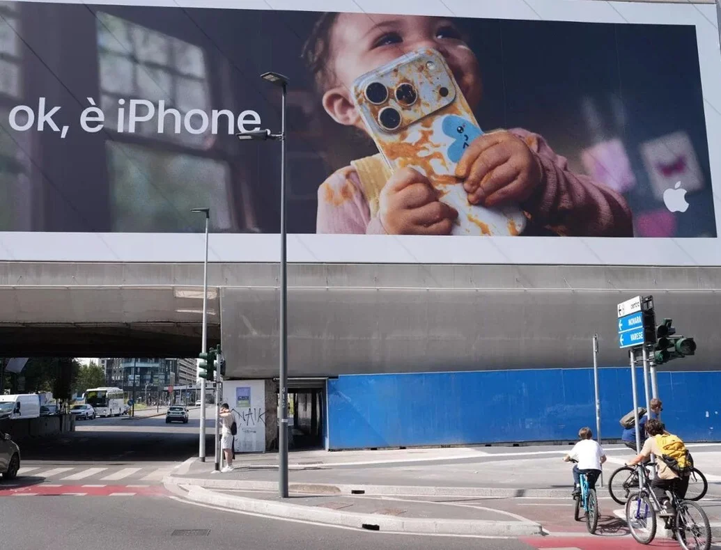 Η πινακίδα της Apple με το αρκετά μικρό παιδί να κρατάει ένα iPhone